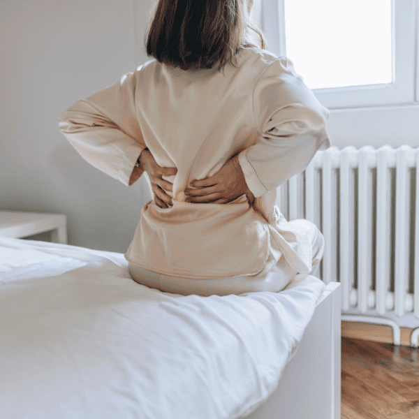 Woman sitting on bed with a backache