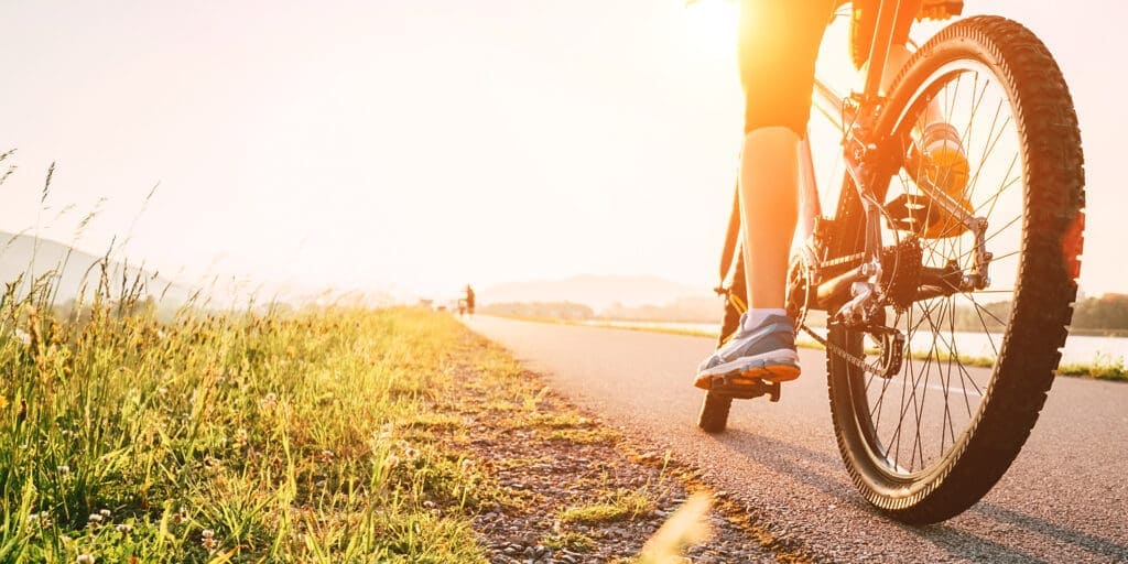 Woman peddling on bicycle at sunset