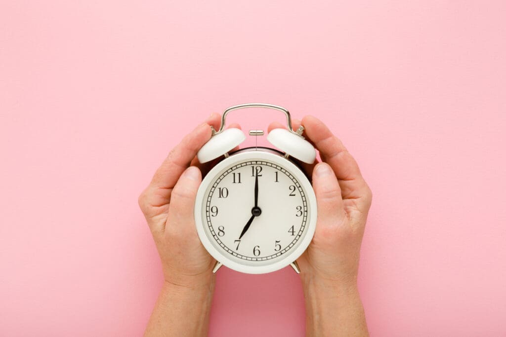 Mature woman's hands around an alarm clock
