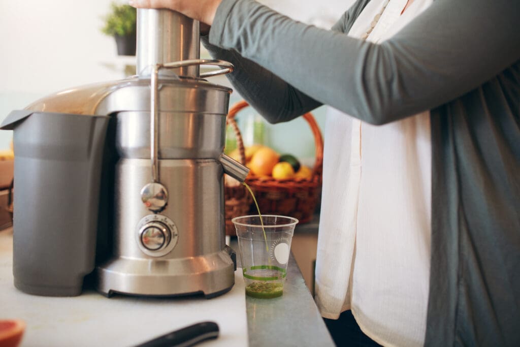 close up of woman making fruit juice using juicer