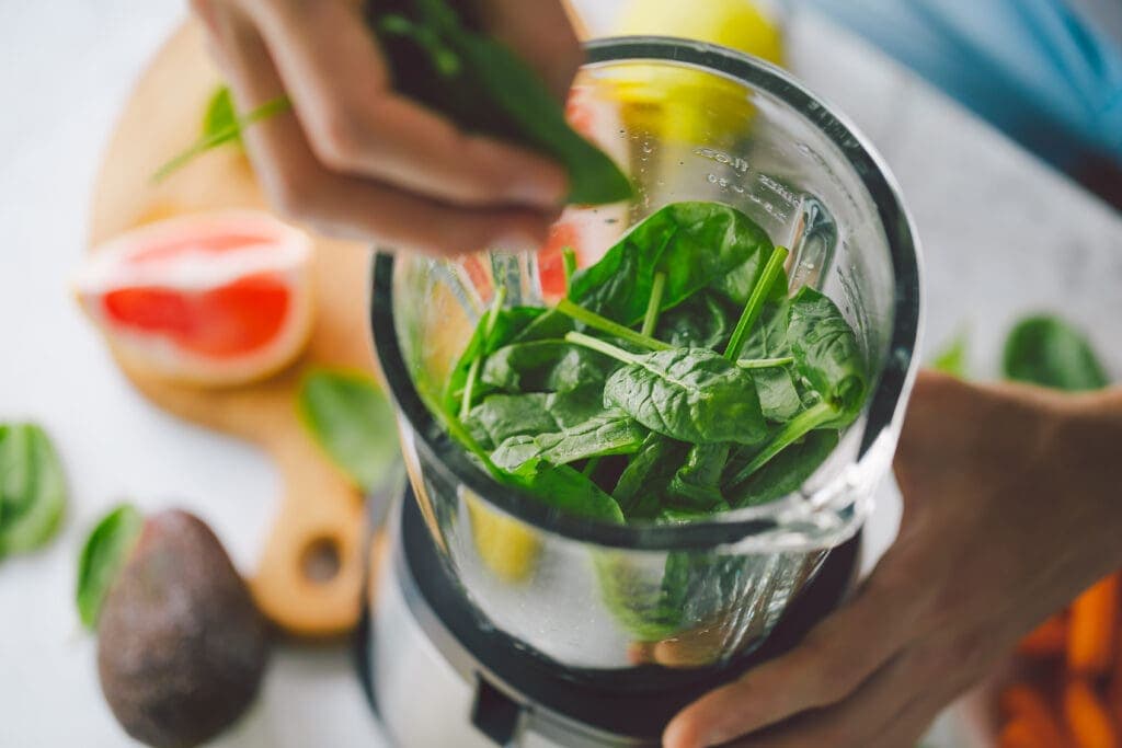 Close up of person creating smoothie with fruits and spinach