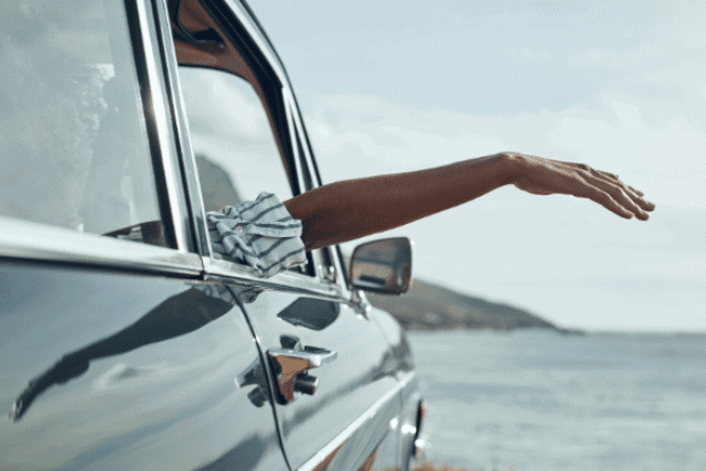 Hand out the window carefree at the beach
