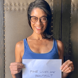 woman holds up sign that says fine lines are beautiful