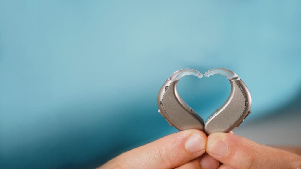 Hearing aids in hands making heart shape
