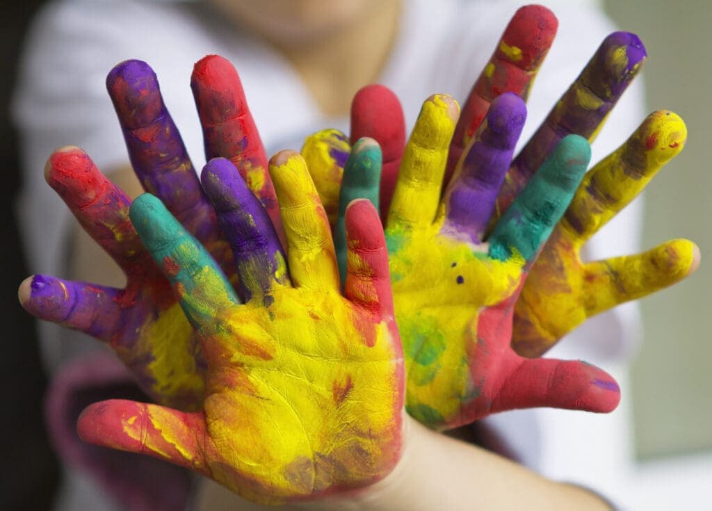 close up of hands painted in rainbow colors