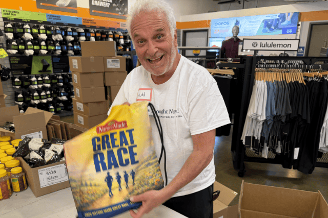 Happy man holding a motivational race book in a sporting goods store.