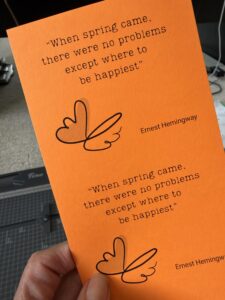 Bright orange motivational quote card with a handwritten-style heart and signature illustration.