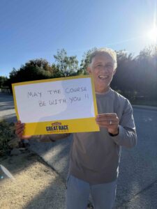 May the course be with you! Motivated man holding sign outdoors during Great Race event.